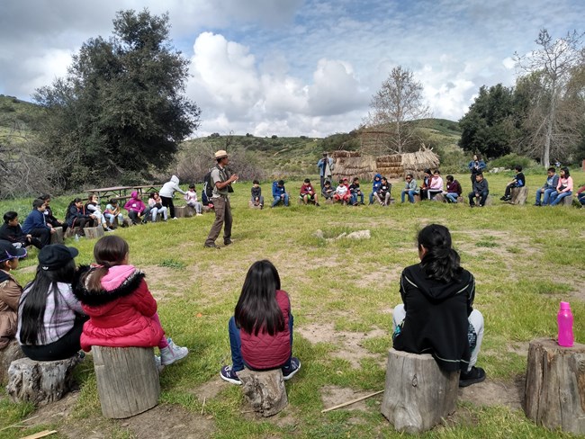 Ranger leading opening talk at log circle with group of student