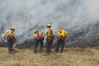 Rangers in fire safe uniforms out on a trail cutting fire.