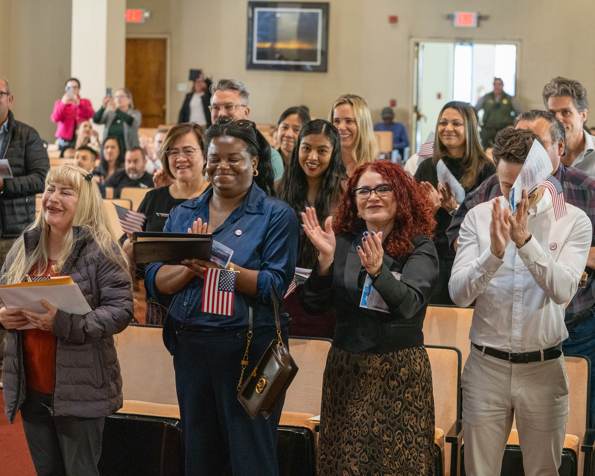 An indoor photo taken at King Gillette Ranch auditorium shows a diverse group of new citizens engaged and smiling during the sixth naturalization ceremony.