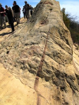 Hikers stand next a fault near Castro Crest.