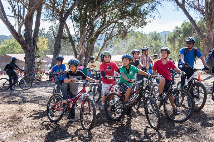 A group of youth stand with their mountain bikes.