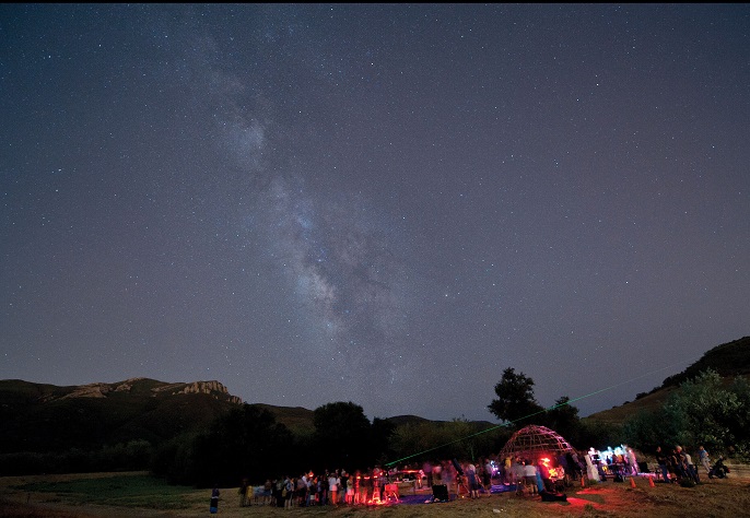 a group of people look up at the starry night sky