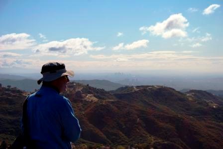 A hiker enjoys the view from a lookout just below Saddle Peak. Out in the distance is Downtown Los Angeles.