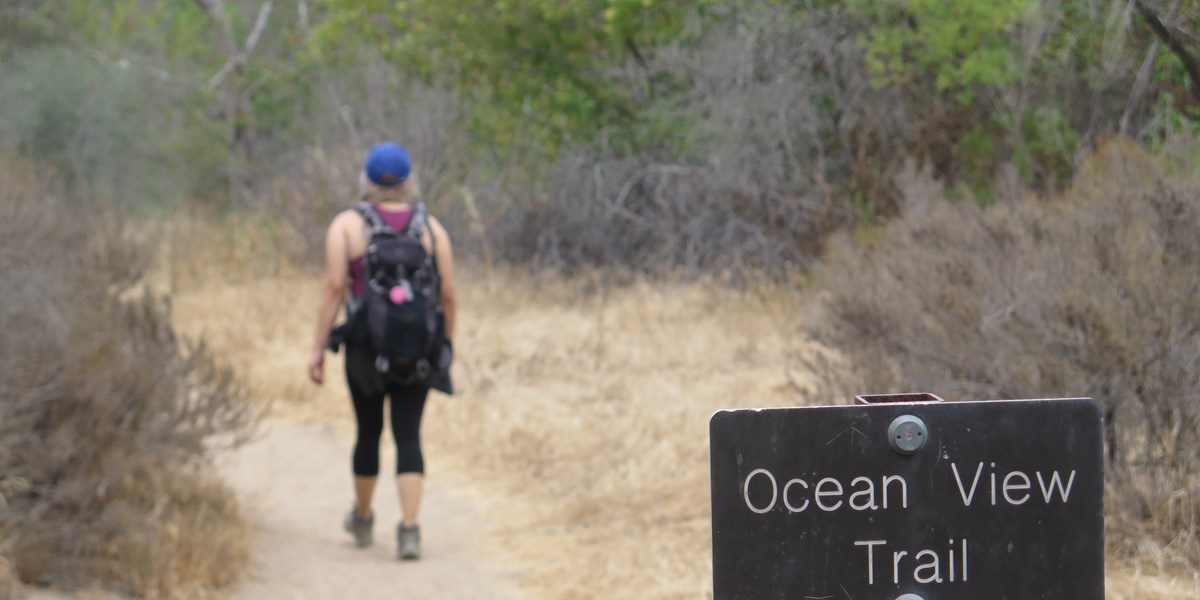 Ocean View Trail sign with hiker in the background
