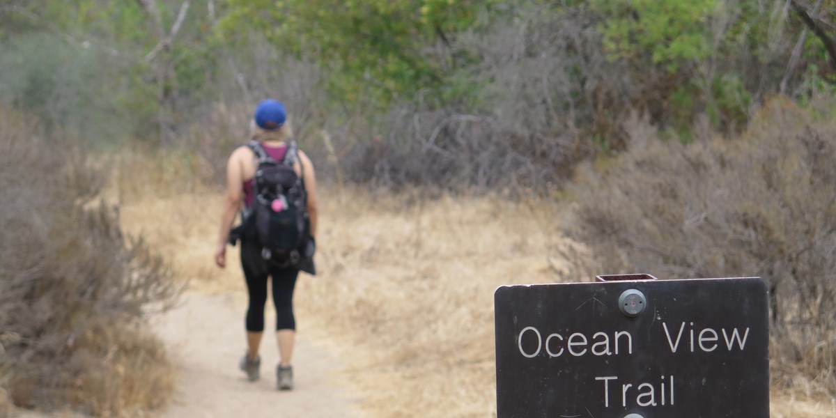Ocean View Trail sign with hiker in the background