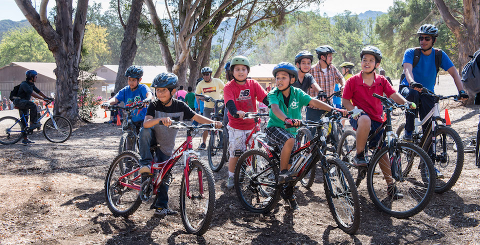 A group of youth stand with their mountain bikes A group of youth stand with their mountain bikes