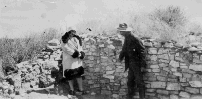 W.H. "Doc" Smith, first custodian of Gran Quivira National Monument, entertains a well-dressed park visitor.