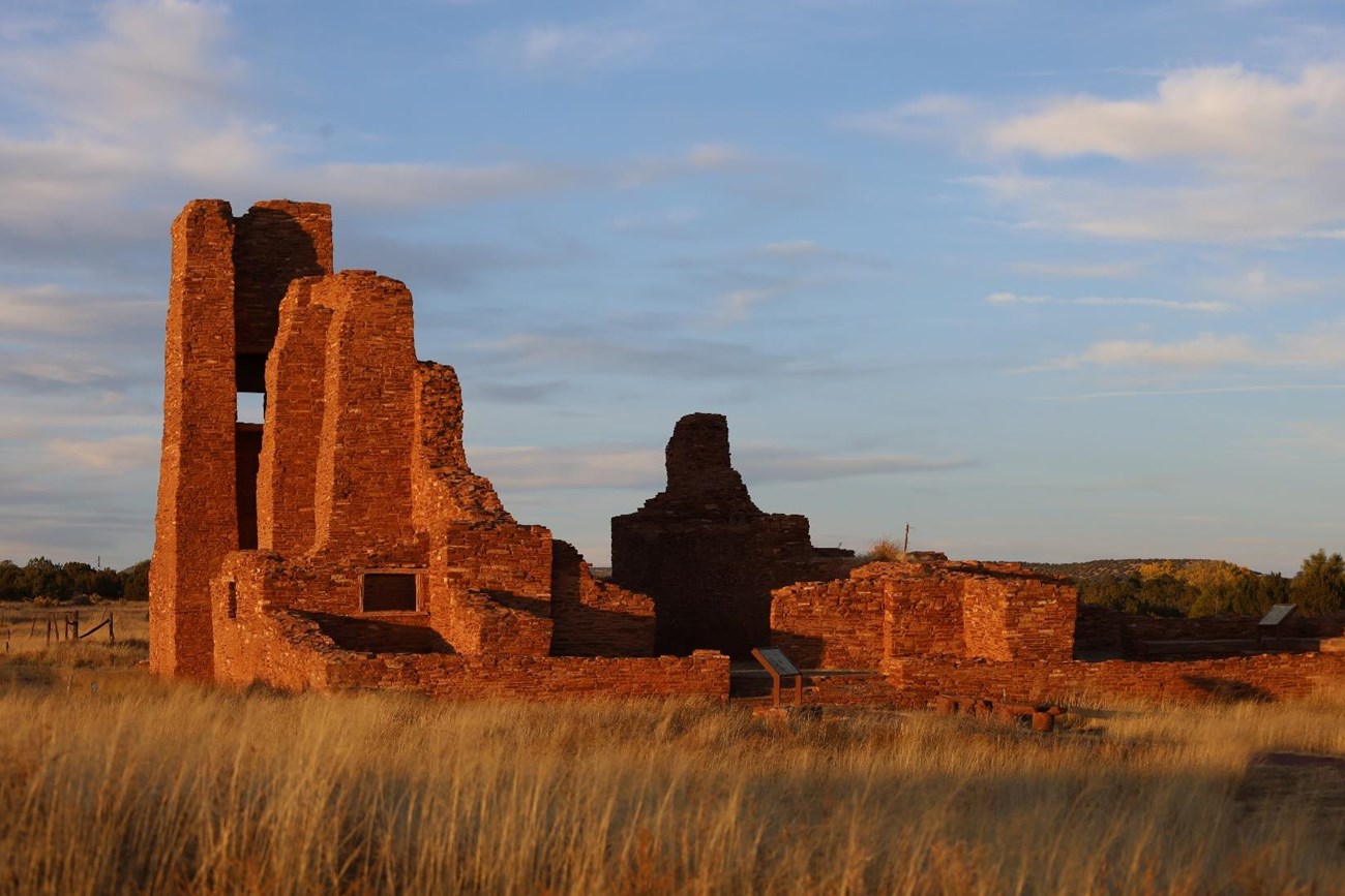 Ruins of a stone building lit by low sunlight.