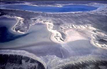 An aerial view of the Estancia Basin showing a shallow lake and salt deposits.