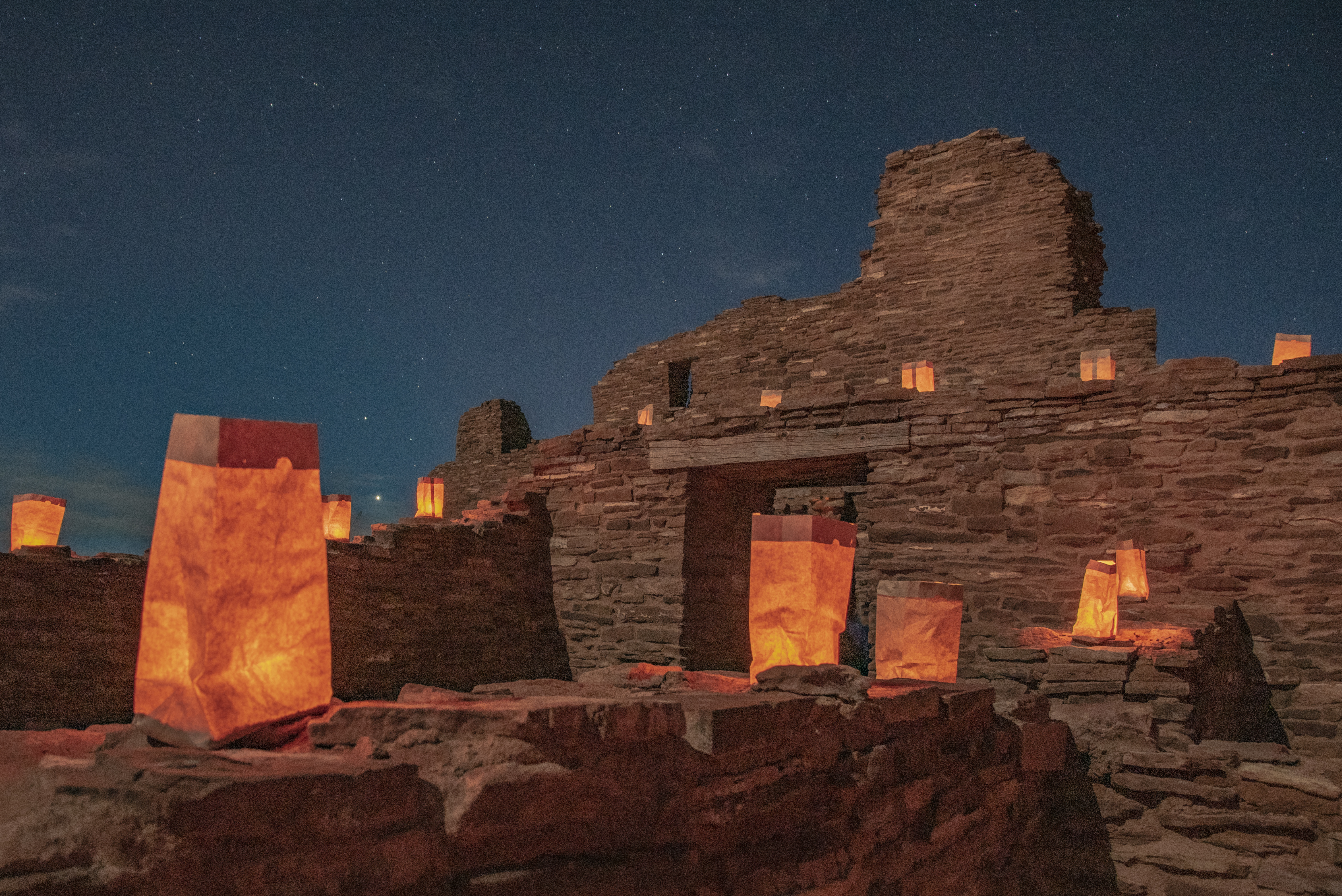 Abo Luminaria 2019 Lit luminarias with red sandstone ruins in the background.
