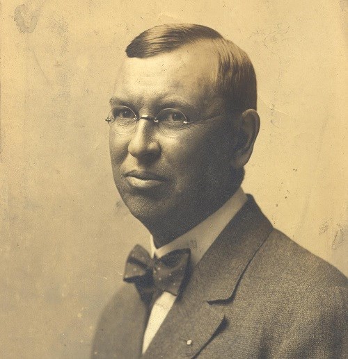 A middle-aged man with glasses, short, straight hair, bow tie, and suit jacket.