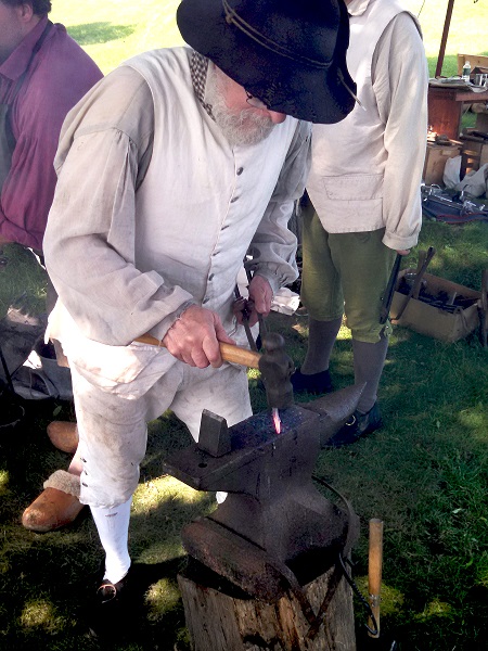 18th Century Blacksmith pounding heated metal on anvil
