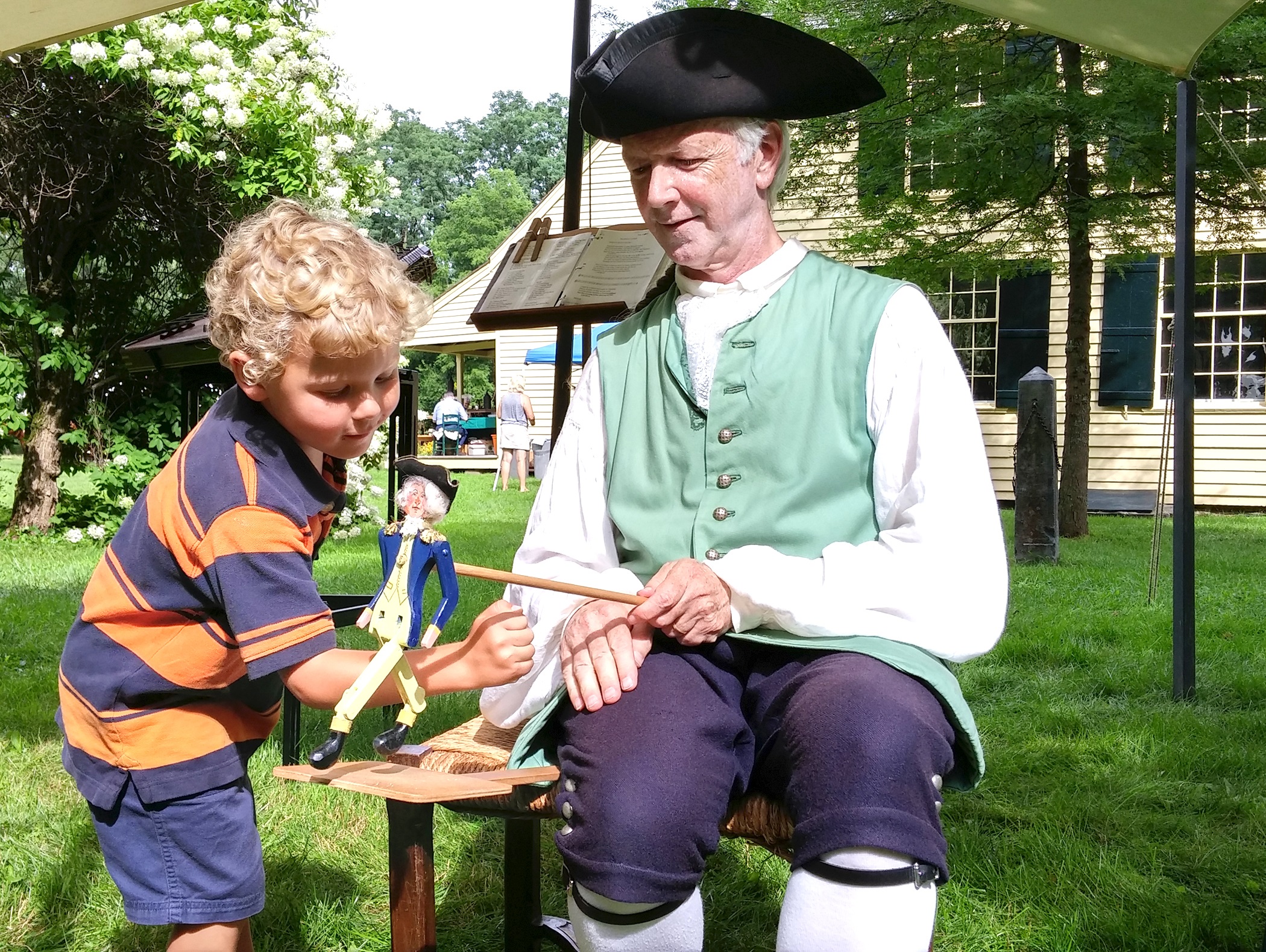 Young boy plays with 18th Century wooden dancing man