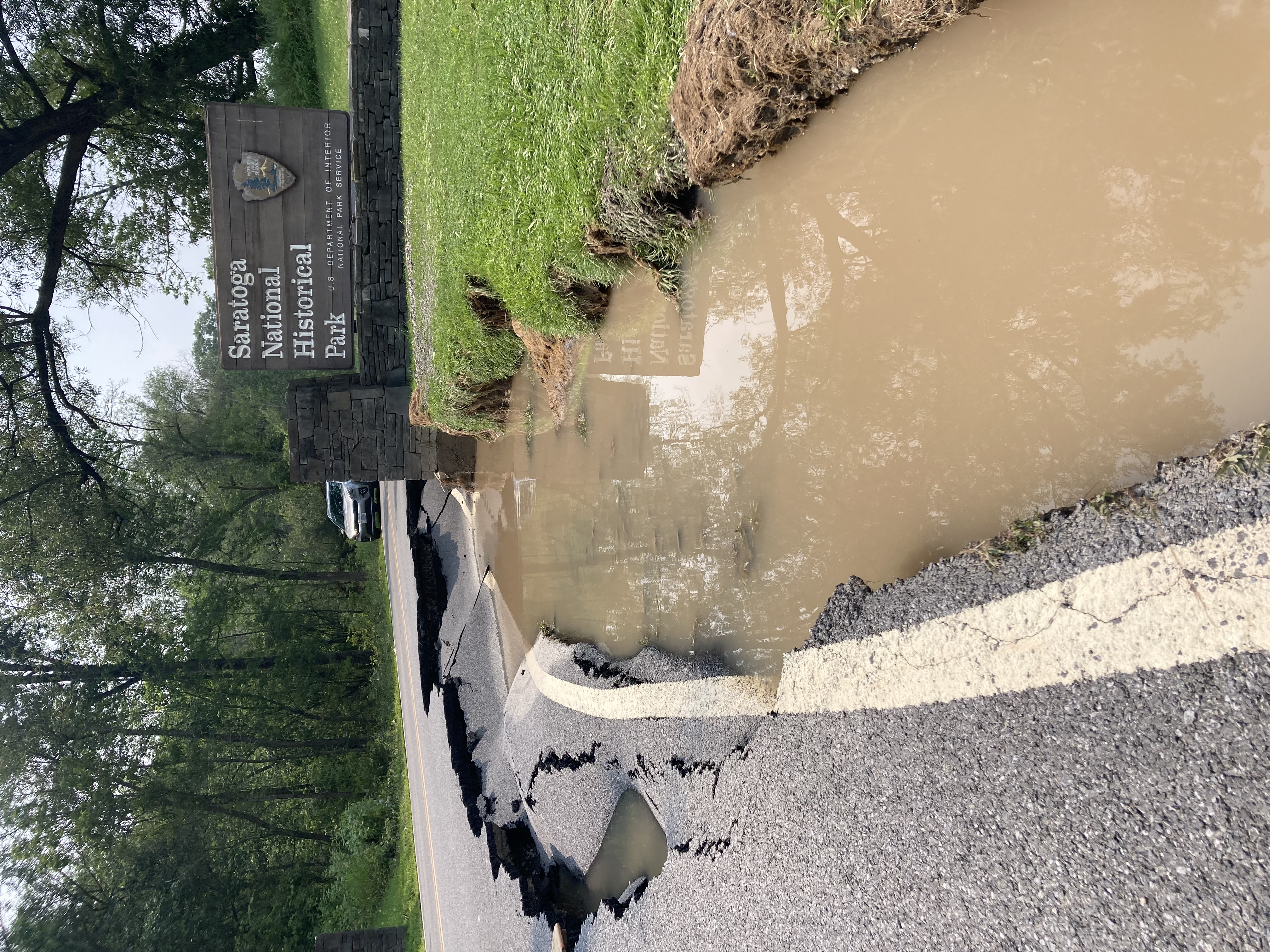 Washed out road with standing water along right side.