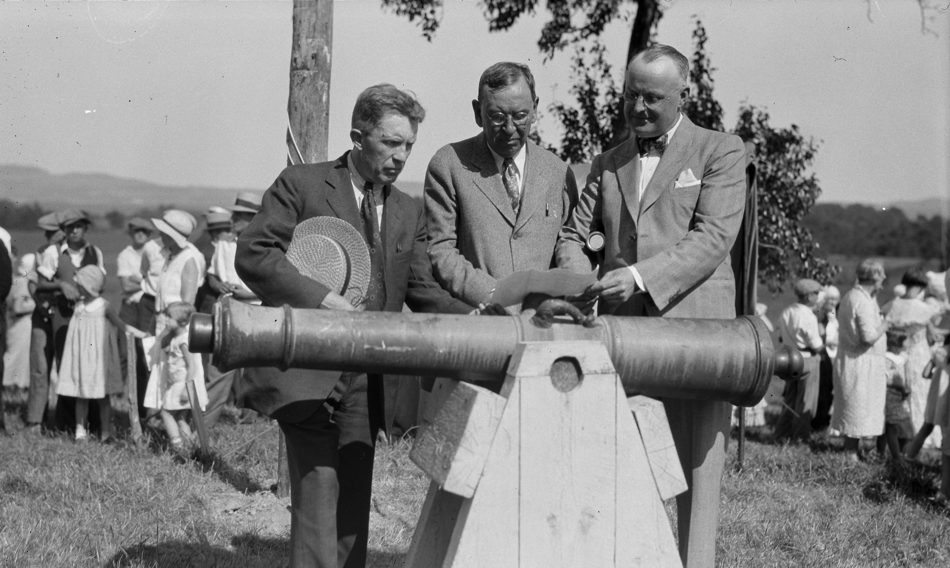 Black and white photo showing two men posed next to an old cannon