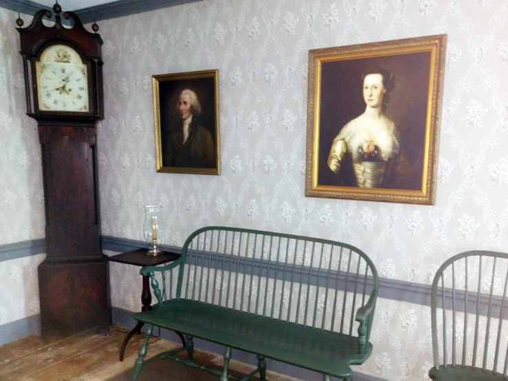 Tall clock stands in the corner of the hallway of the Schuyler House Tall wooden clock in corner of hall, two portraits hang on wall