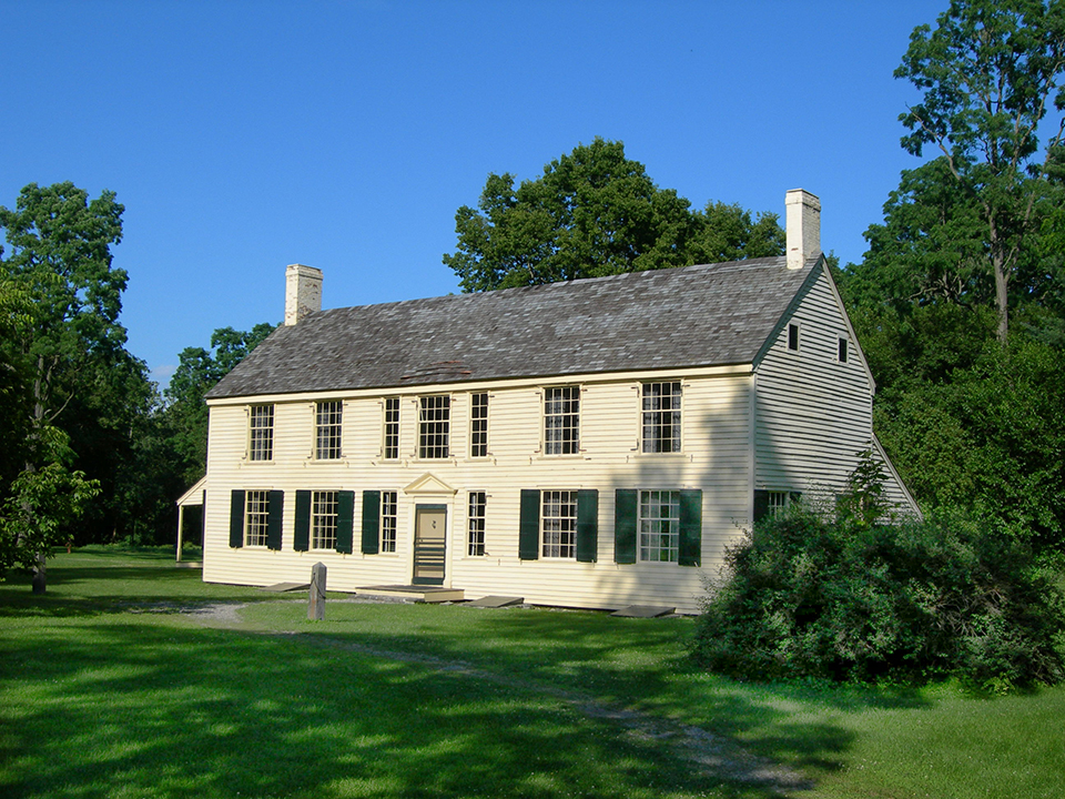Schuyler House Large yellow house shown from a slight angle. Surrounded by green grass and trees.