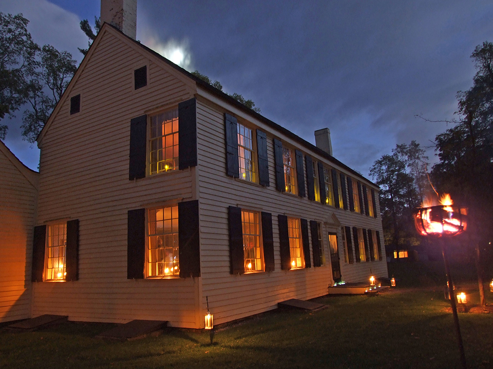 Schuyler House lit by candlelight front of historic yellow house lit by candlelight