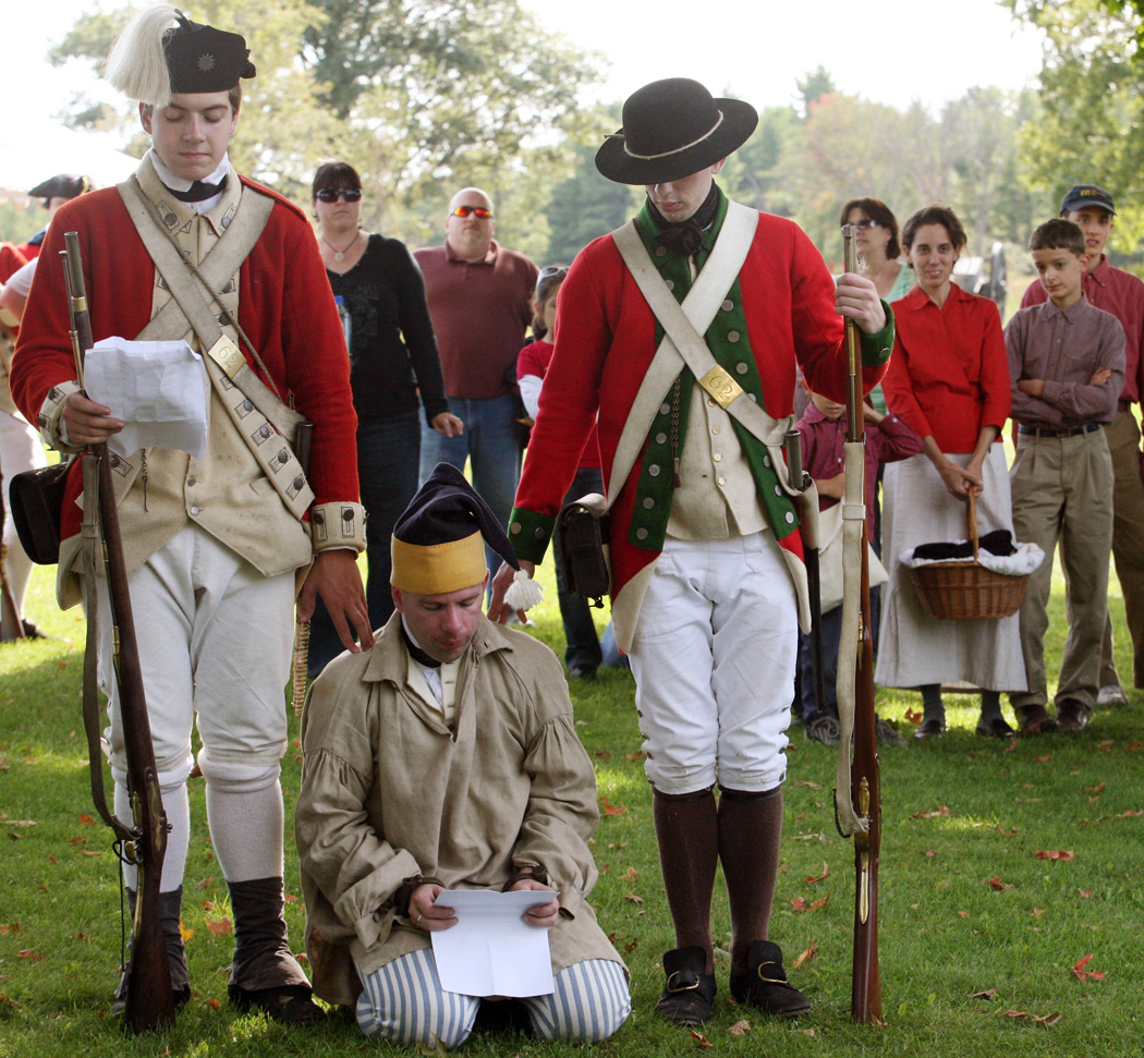 Revolution spy kneeling on the ground surrounded by two standing soldiers