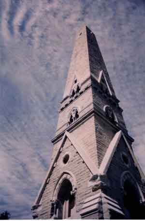 View of the outside of Saratoga Monument.  The stone obelisk reaches high into the cloud flecked blue sky.