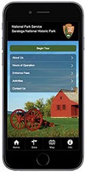 Simulated cell phone image displaying a park tour app. A small, historic, red house, a red cannon carriage, green lawn and blue sky are also visible.