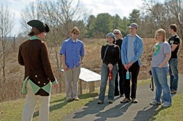 A Battlefield Guide in Revolutionary War American uniform speaks with a group of visitors. A Battlefield Guide in Revolutionary War American uniform speaks with a group of visitors.