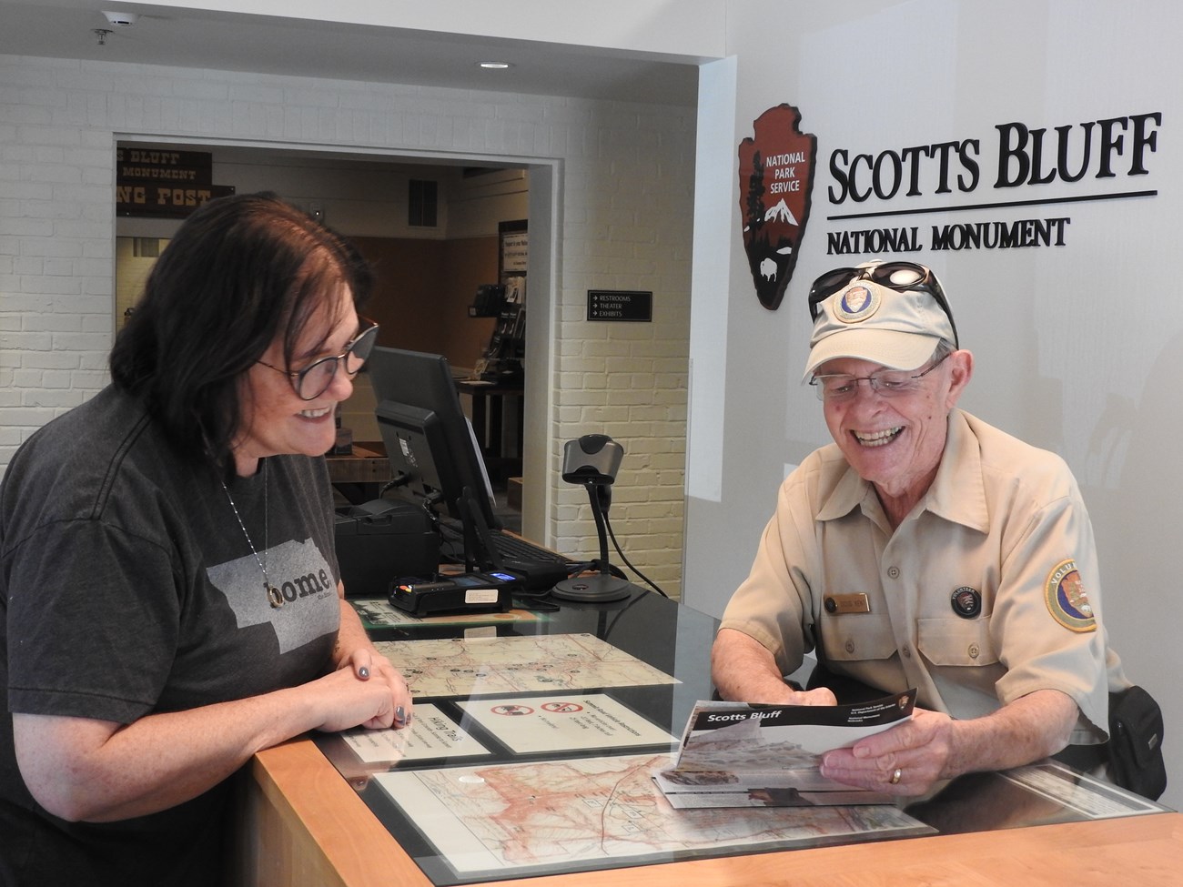A volunteer helps a woman from behind an information desk.