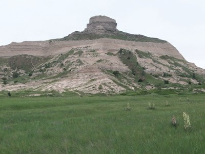 A sandstone knob rises above the green prairie below.