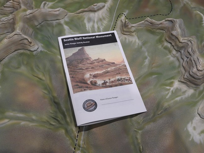 A Scotts Bluff National Monument Junior Ranger booklet rests on a relief map of the monument.