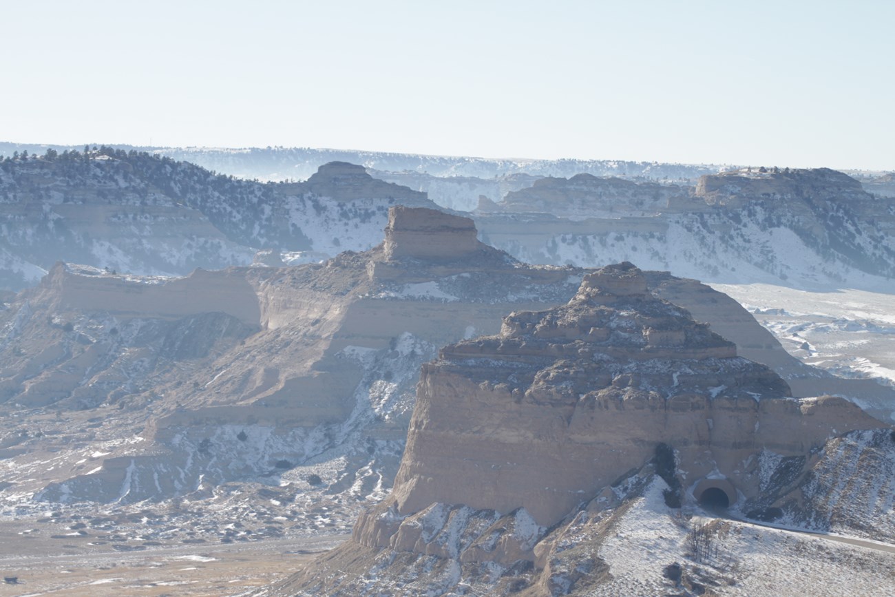 Snow covers the shaded areas of a sandstone bluff.