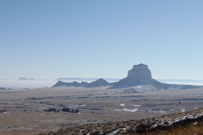A solitary butte rises above the surrounding prairie.