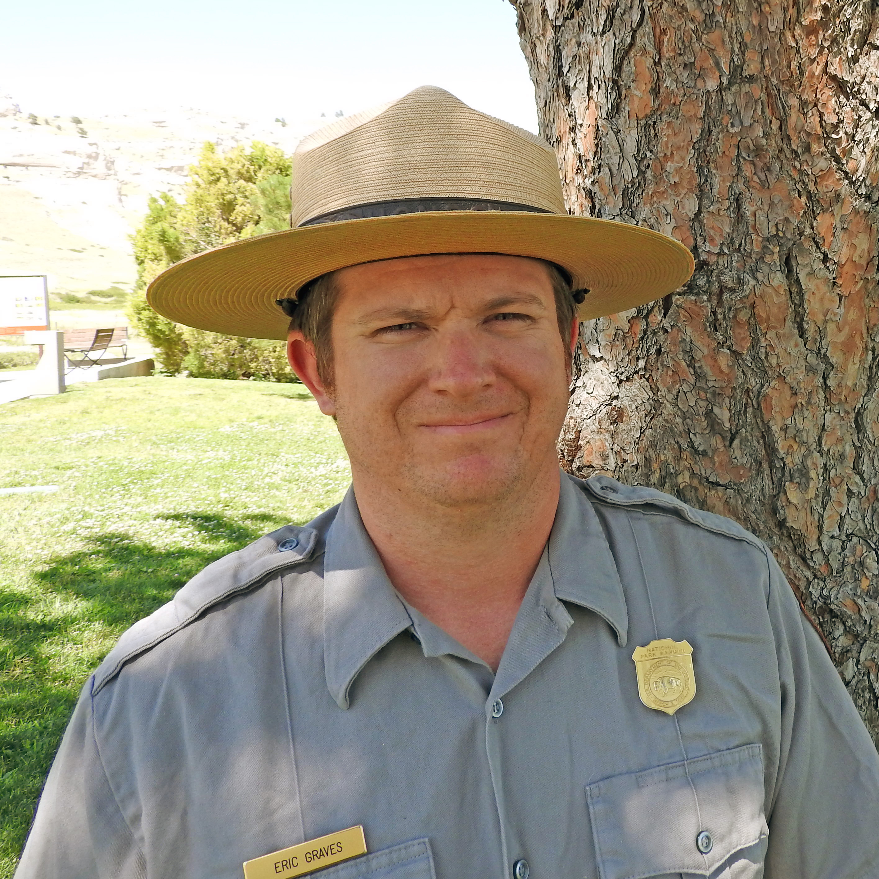 Join Park Ranger Eric Graves for "Wheel, Legs, and Sail" at 7PM on Friday, August 2nd at 7PM. A park ranger stands in the shade of a pine tree.