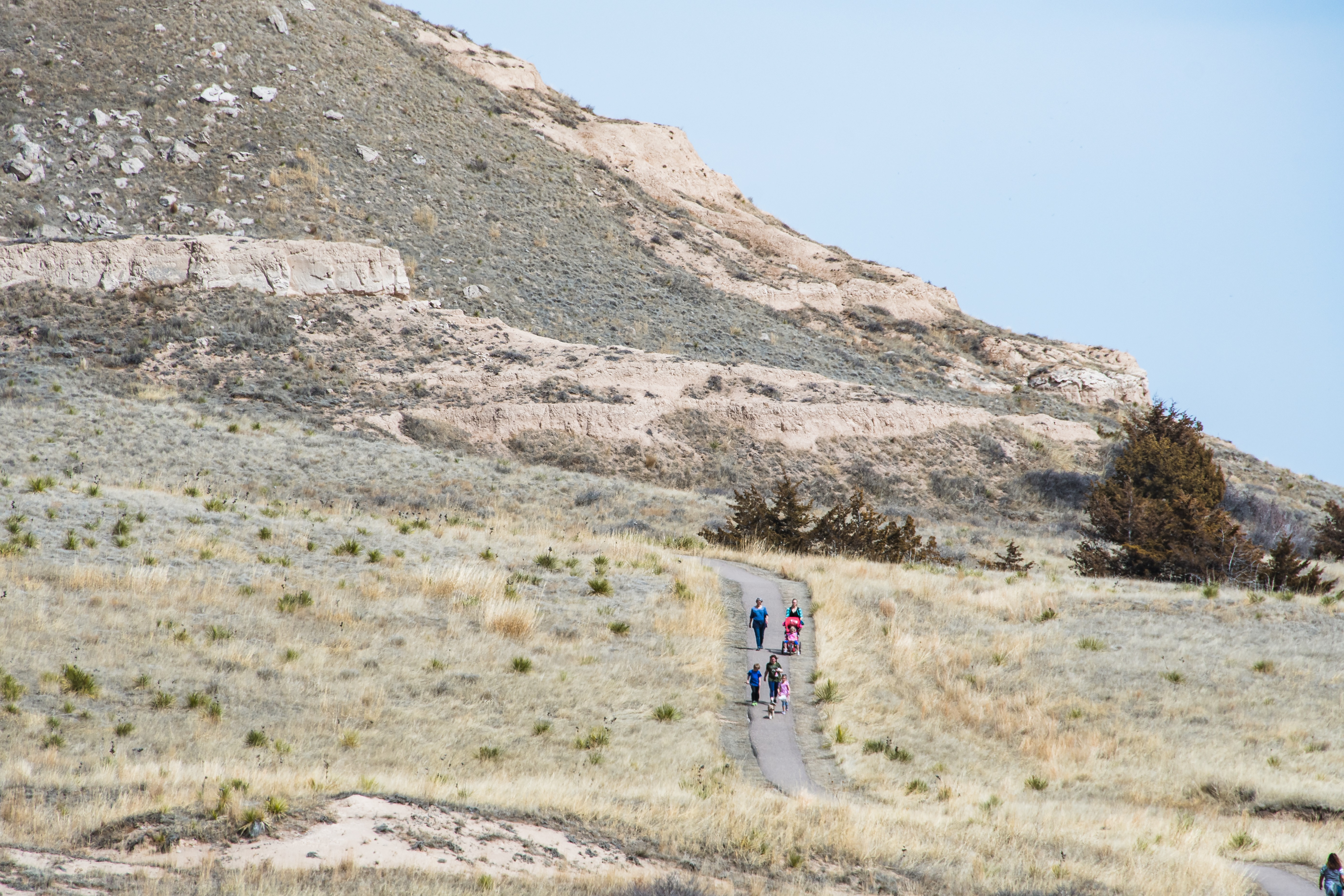 The Saddle Rock Trail has reopened after a 53-day long closure due to a rockslide. A group of people walk a paved trail.