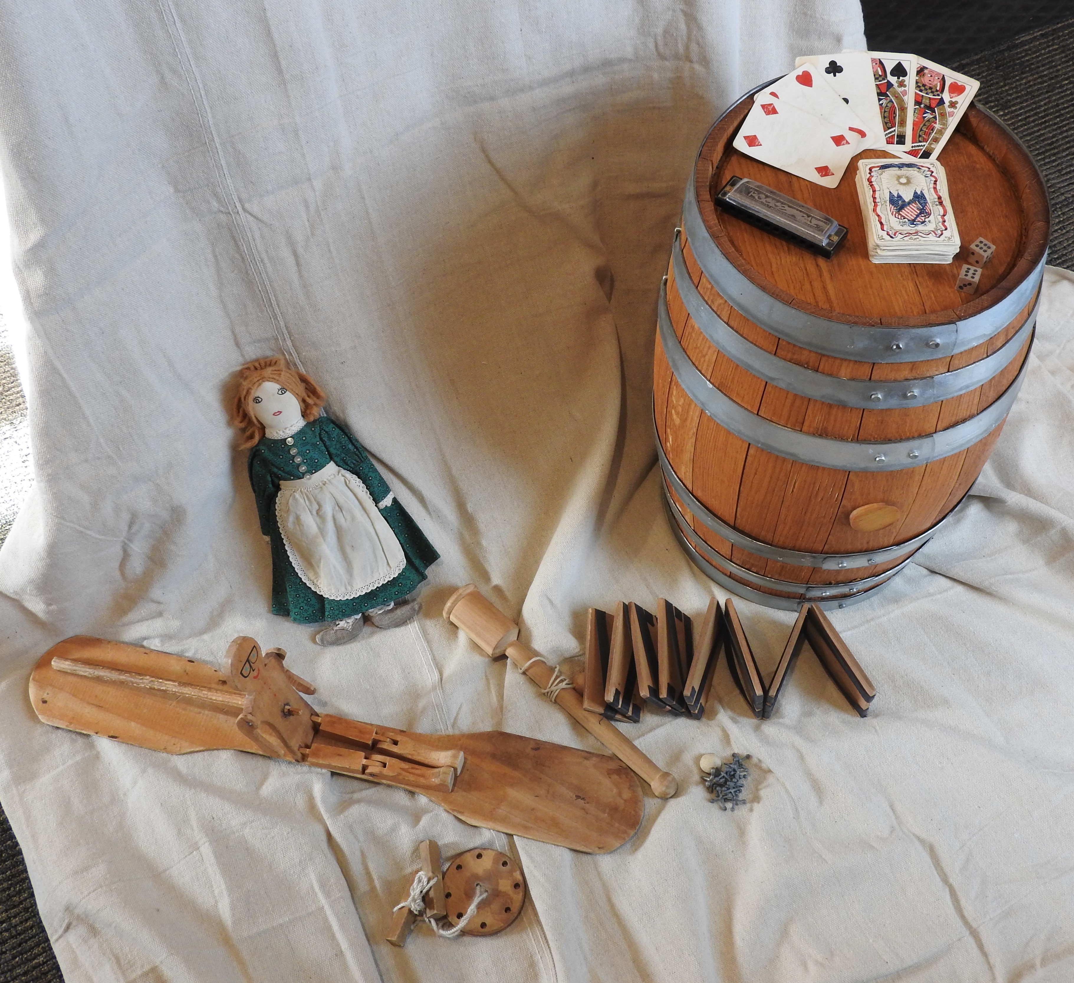 Several small toys and games, including a Jacob's Ladder and deck of playing cards, are spread out on canvas.