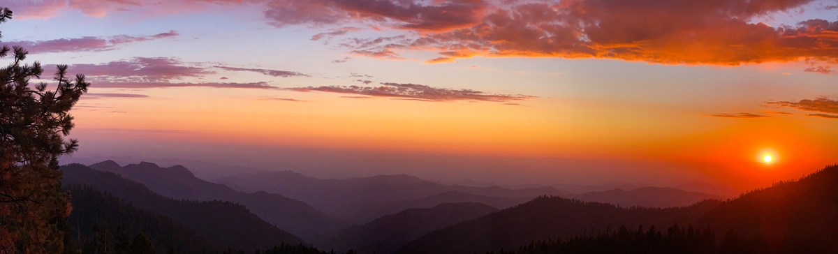 The sunsets creating a display of colors from yellow to orange to pink and purple with mountain silhouettes in the distance.