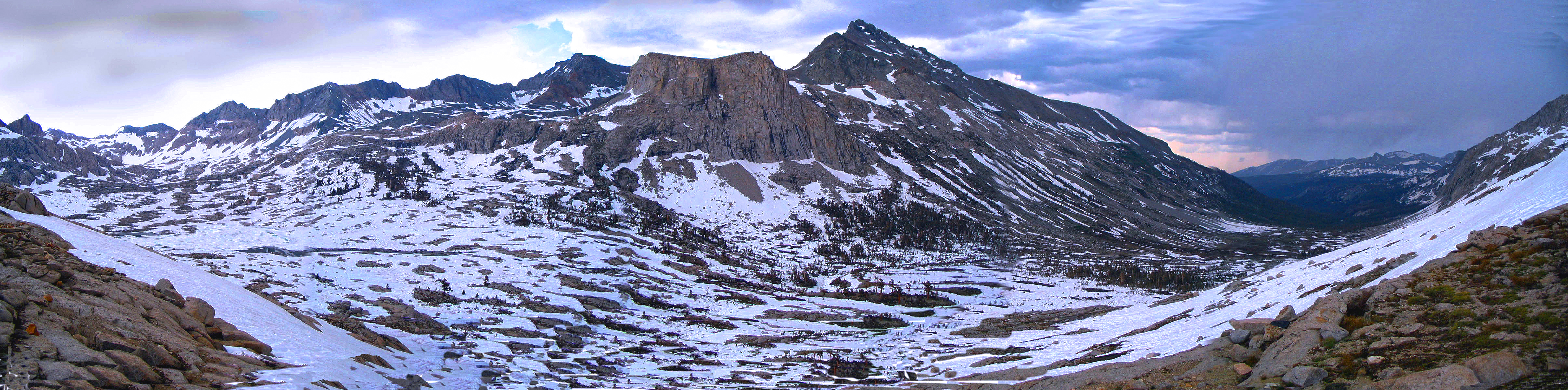A panorama of a large rocky basin covered in snow.