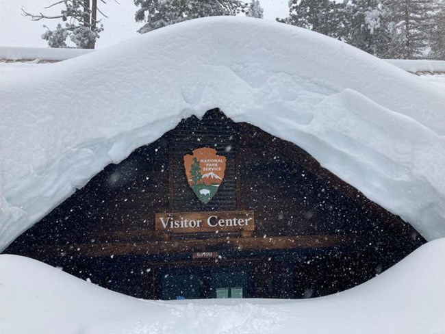 A visitor center completely covered in snow, piled almost 20 feet high.