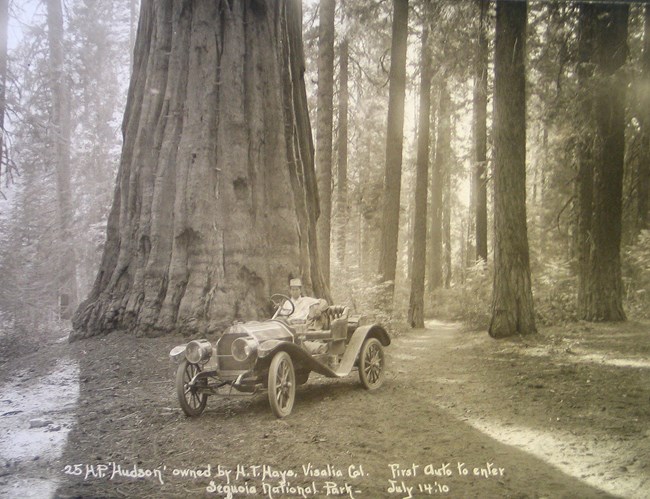 an early automobile driver sits in his parked vehicle