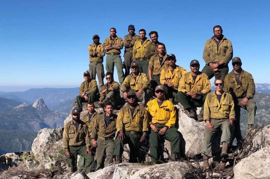 19 hotshots pose on a rugged mountaintop