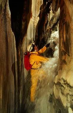 Caver stands in front of a waterfall in Lilburn Cave