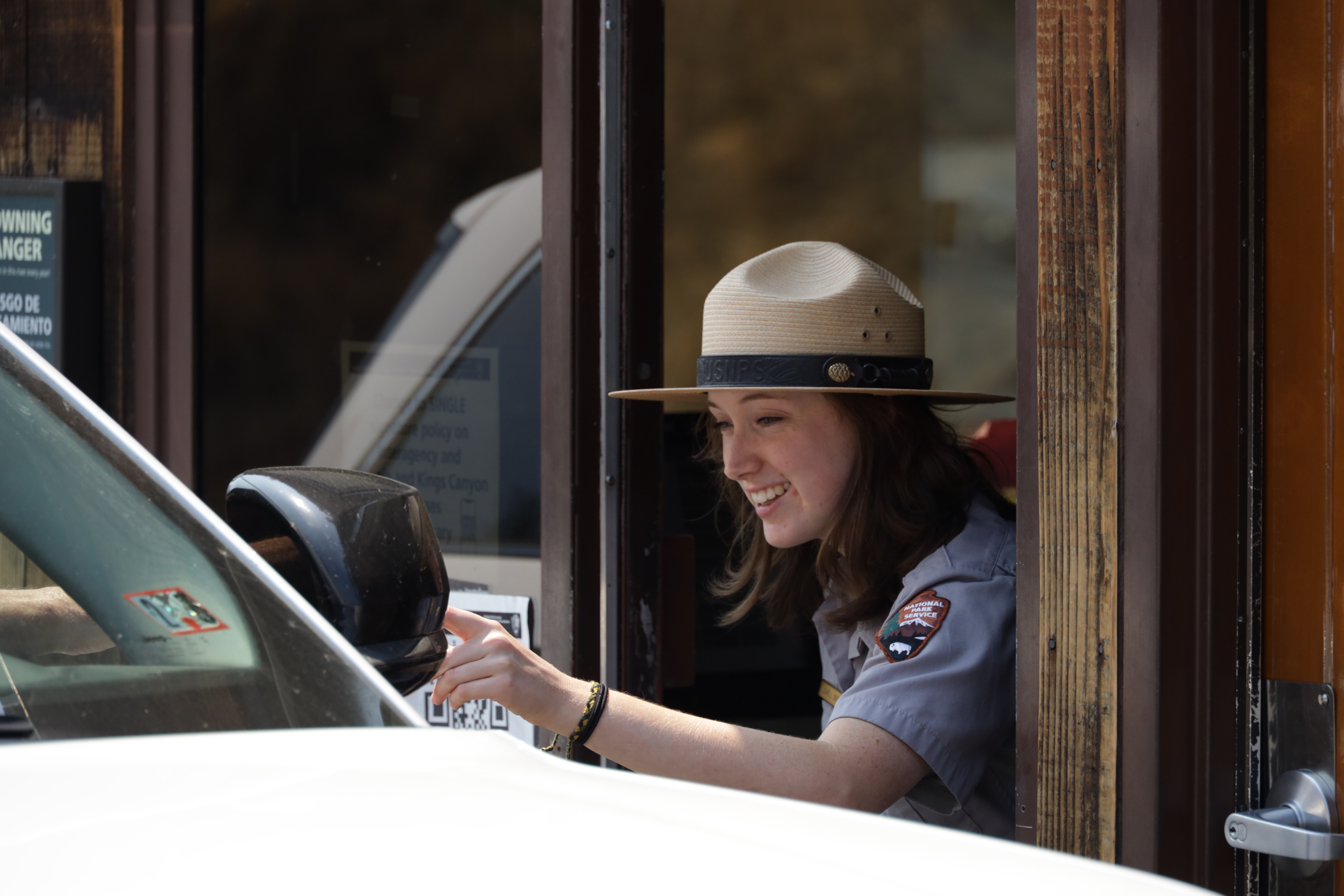 A uniformed park ranger greets a visitor at the entrance station.