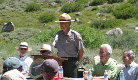 Chief Park Ranger Hendricks, in uniform, stands to address the audience.