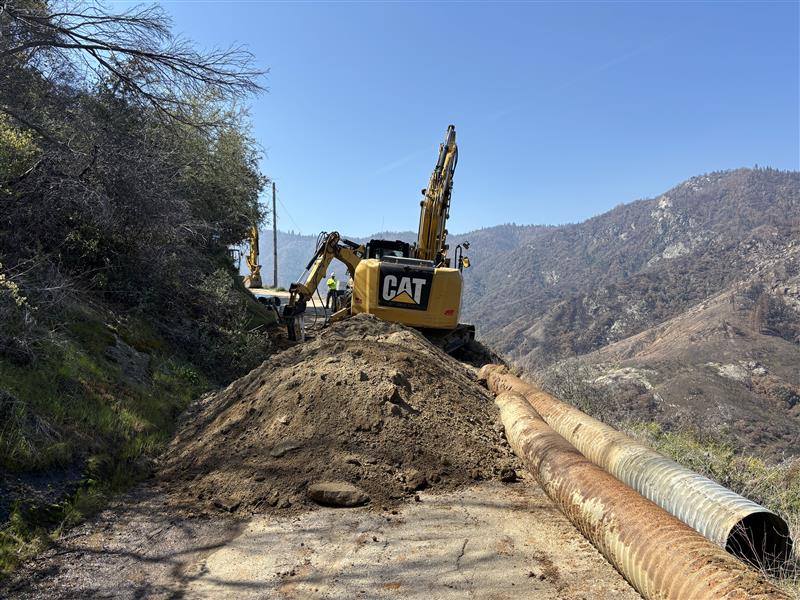 Road construction crews use an excavator and backhoe to remove old culverts and break rock for installation of new culverts along Mineral King Road.