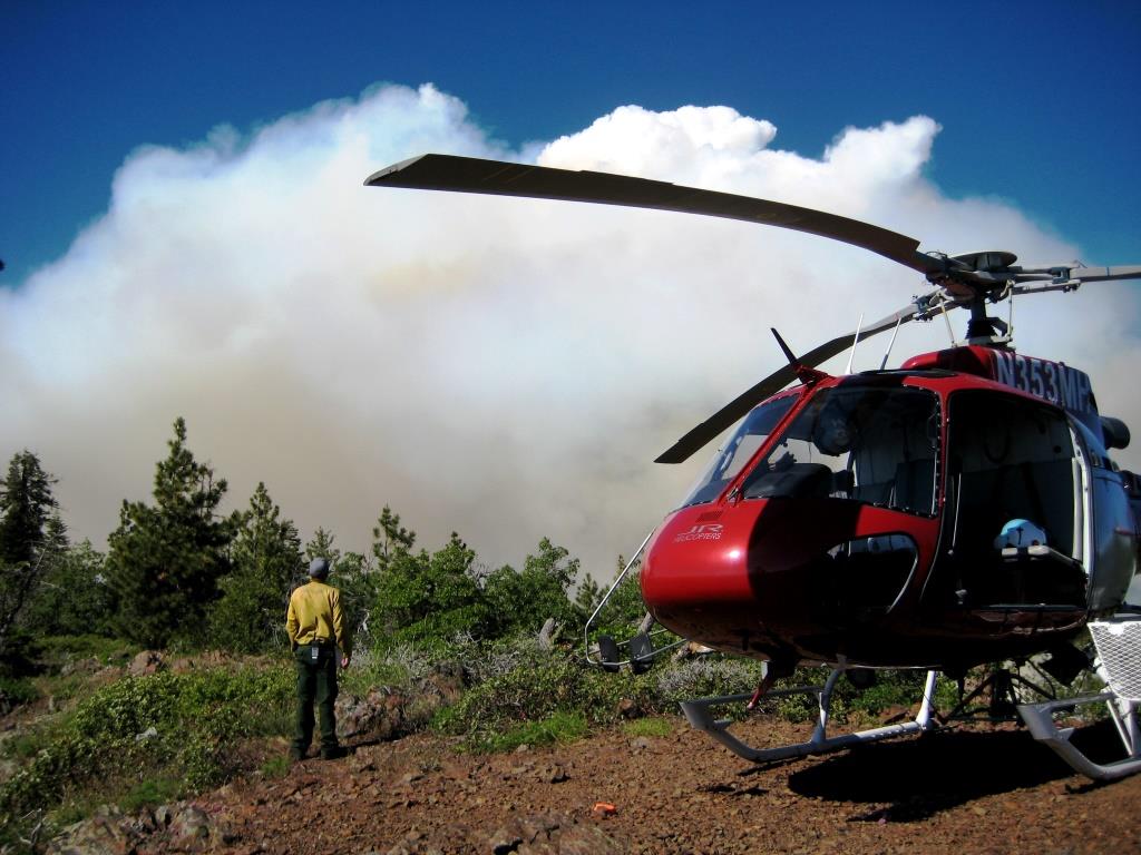 A helitack firefighter observes smoke during a prescribed burn.