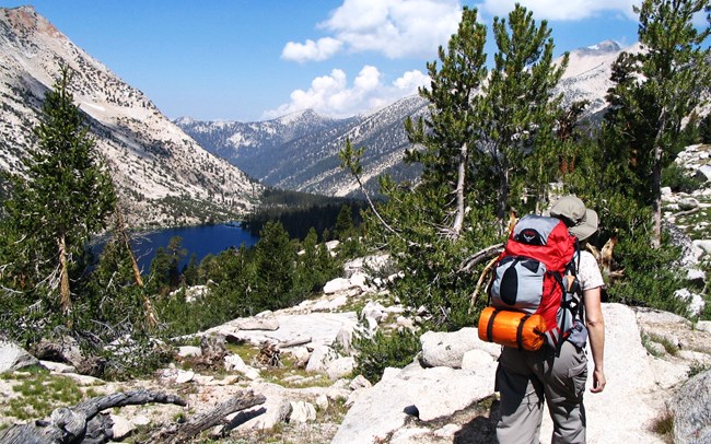 A backpacker hikes near a mountain lake