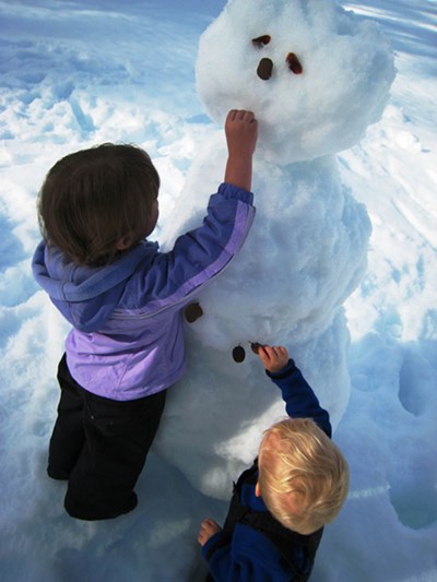 Two children build a snowman.
