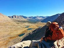 A backpacker looks over a vast alpine landscape