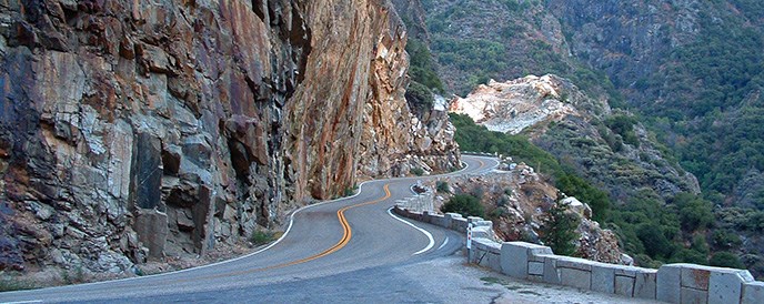 A steep cliff rises up along the side of a highway