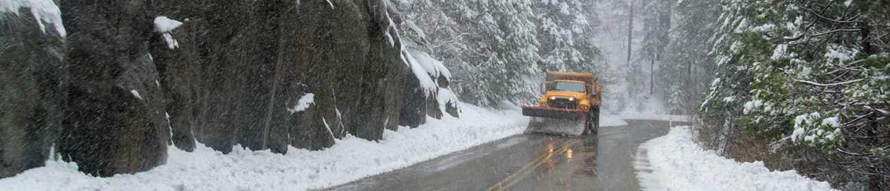 A snowplow drives along a snowy road