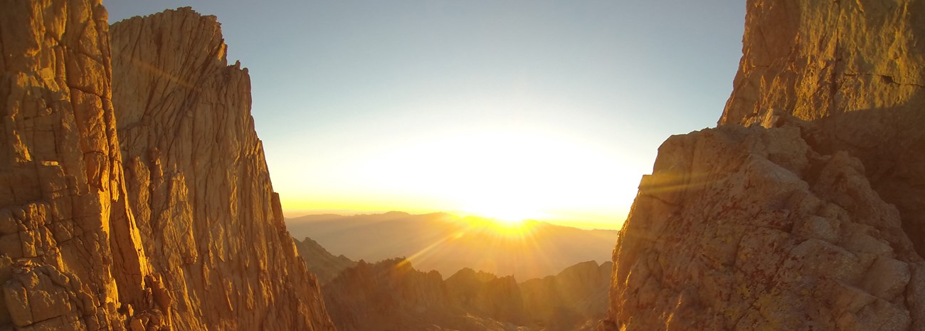 a sunrise illuminates rocky peaks